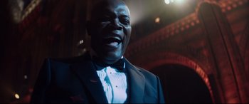 Movie still from “Hitman's Wife's Bodyguard” (2021), directed by Patrick Hughes – A person wearing a suit and a bow tie; Close Up shot, Low angle