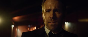 Movie still from “Hitman's Wife's Bodyguard” (2021), directed by Patrick Hughes – A person wearing a suit and tie; Close Up shot, Over the shoulder angle