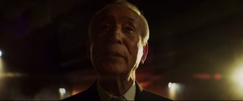 Movie still from “Hitman's Wife's Bodyguard” (2021), directed by Patrick Hughes – An older man in a suit and tie looking into the distance; Close Up shot, Low angle