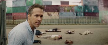 Movie still from “Hitman's Wife's Bodyguard” (2021), directed by Patrick Hughes – A man standing in front of a group of dead bodies; Close Up shot, Over the shoulder angle