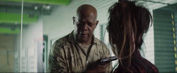 Movie still from “Hitman's Wife's Bodyguard” (2021), directed by Patrick Hughes – An older man holding a gun in a room; Close Up shot, Over the shoulder angle