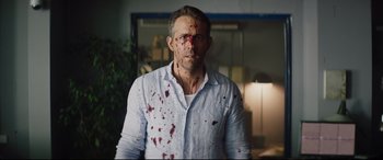 Movie still from “Hitman's Wife's Bodyguard” (2021), directed by Patrick Hughes – A man with blood all over his face and neck; Close Up shot, Over the shoulder angle