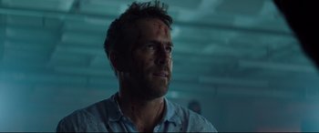Movie still from “Hitman's Wife's Bodyguard” (2021), directed by Patrick Hughes – A person wearing a shirt with blood on his face; Close Up shot, Over the shoulder angle