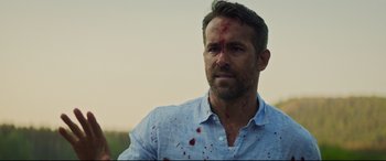 Movie still from “Hitman's Wife's Bodyguard” (2021), directed by Patrick Hughes – A person with blood on his face; Close Up shot, Over the shoulder angle