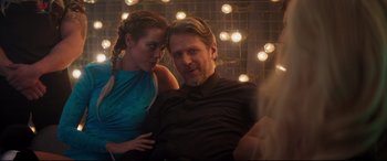 Movie still from “Hitman's Wife's Bodyguard” (2021), directed by Patrick Hughes – A man and a woman sitting next to each other in front of lights; Medium shot, Over the shoulder angle