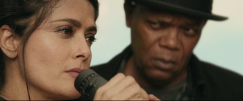 Movie still from “Hitman's Wife's Bodyguard” (2021), directed by Patrick Hughes – A woman holding a microphone while a man holds a microphone; Close Up shot, Over the shoulder angle