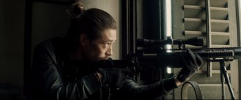 Movie still from “Hitman's Wife's Bodyguard” (2021), directed by Patrick Hughes – A man holding a rifle in a room; Close Up shot, Over the shoulder angle