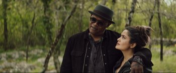 Movie still from “Hitman's Wife's Bodyguard” (2021), directed by Patrick Hughes – A man and a woman standing next to each other in front of a tree; Close Up shot, Over the shoulder angle
