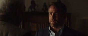 Movie still from “Hitman's Wife's Bodyguard” (2021), directed by Patrick Hughes – A person wearing a suit and tie; Close Up shot, Over the shoulder angle