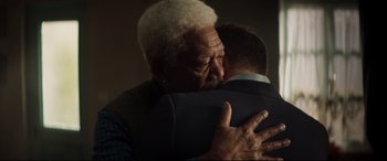 Movie still from “Hitman's Wife's Bodyguard” (2021), directed by Patrick Hughes – An older man hugging a younger man in a room; Close Up shot, Over the shoulder angle