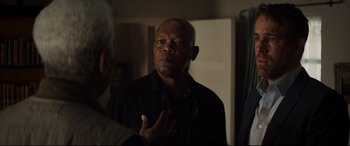 Movie still from “Hitman's Wife's Bodyguard” (2021), directed by Patrick Hughes – An older man talking to a younger man in a room; Close Up shot, Over the shoulder angle