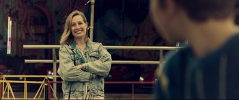 Movie still from “Hitman's Wife's Bodyguard” (2021), directed by Patrick Hughes – A woman standing with her arms crossed smiling; Medium shot, Over the shoulder angle