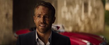 Movie still from “Hitman's Wife's Bodyguard” (2021), directed by Patrick Hughes – A person holding a flower in his mouth; Close Up shot, Over the shoulder angle