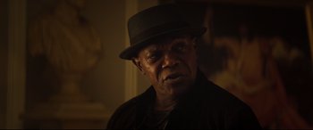 Movie still from “Hitman's Wife's Bodyguard” (2021), directed by Patrick Hughes – A man wearing a black hat and a black jacket; Close Up shot, Over the shoulder angle