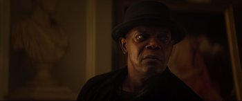 Movie still from “Hitman's Wife's Bodyguard” (2021), directed by Patrick Hughes – A man wearing a black hat and a black jacket; Close Up shot, Over the shoulder angle