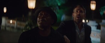 Movie still from “Hitman's Wife's Bodyguard” (2021), directed by Patrick Hughes – A man in a hat and a man in a black shirt; Close Up shot, Over the shoulder angle