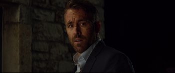 Movie still from “Hitman's Wife's Bodyguard” (2021), directed by Patrick Hughes – A person wearing a suit and tie; Close Up shot, Over the shoulder angle