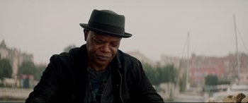 Movie still from “Hitman's Wife's Bodyguard” (2021), directed by Patrick Hughes – An older man wearing a black hat and jacket; Close Up shot, Low angle