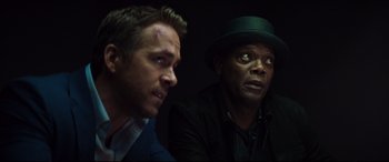 Movie still from “Hitman's Wife's Bodyguard” (2021), directed by Patrick Hughes – Two men sitting next to each other in a dark room; Close Up shot, Over the shoulder angle