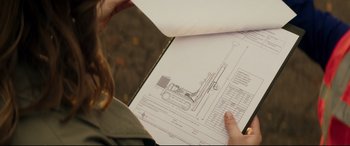 Movie still from “Hitman's Wife's Bodyguard” (2021), directed by Patrick Hughes – A person looking at a drawing of an excavator; Extreme Close Up shot, Overhead angle