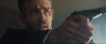 Movie still from “Hitman's Wife's Bodyguard” (2021), directed by Patrick Hughes – A person holding a cell phone; Close Up shot, Over the shoulder angle