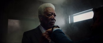 Movie still from “Hitman's Wife's Bodyguard” (2021), directed by Patrick Hughes – An older man in a suit adjusting his tie; Close Up shot, Low angle