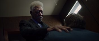 Movie still from “Hitman's Wife's Bodyguard” (2021), directed by Patrick Hughes – An older man wearing a suit and tie; Close Up shot, Over the shoulder angle