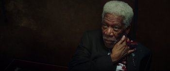 Movie still from “Hitman's Wife's Bodyguard” (2021), directed by Patrick Hughes – An older man in a black suit and white beard; Close Up shot, High angle