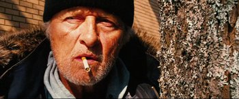 Movie still from “Hobo with a Shotgun” (2011), directed by Jason Eisener – An older man with a cigarette in his mouth; Close Up shot, Low angle