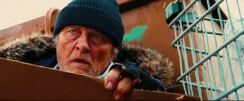 Movie still from “Hobo with a Shotgun” (2011), directed by Jason Eisener – An old man wearing a blue hat and a fur coat; Close Up shot, Low angle