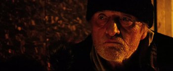 Movie still from “Hobo with a Shotgun” (2011), directed by Jason Eisener – An old man with a beard wearing a black hat; Close Up shot, Low angle
