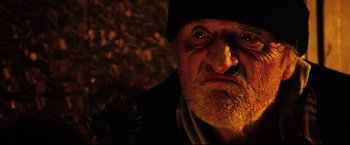 Movie still from “Hobo with a Shotgun” (2011), directed by Jason Eisener – An old man with a beard wearing a black hat; Close Up shot, Low angle