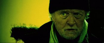 Movie still from “Hobo with a Shotgun” (2011), directed by Jason Eisener – An old man with a beard and a black hat; Close Up shot, Low angle