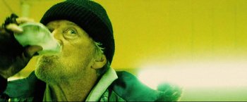 Movie still from “Hobo with a Shotgun” (2011), directed by Jason Eisener – A person wearing a hat with a flashlight; Close Up shot, Low angle