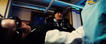Movie still from “Hobo with a Shotgun” (2011), directed by Jason Eisener – An old man sitting in a chair on a bus; Medium shot, Low angle