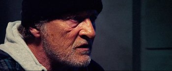 Movie still from “Hobo with a Shotgun” (2011), directed by Jason Eisener – An older man with a beard and a hat; Close Up shot, Low angle