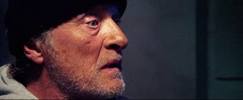 Movie still from “Hobo with a Shotgun” (2011), directed by Jason Eisener – An older man with a beard and a hat; Extreme Close Up shot, Low angle