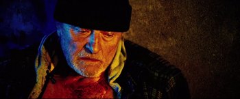 Movie still from “Hobo with a Shotgun” (2011), directed by Jason Eisener – An old man with a beard and a black hat; Close Up shot, High angle