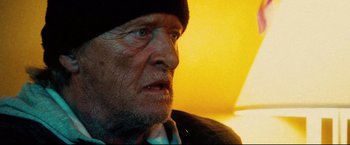 Movie still from “Hobo with a Shotgun” (2011), directed by Jason Eisener – An older man wearing a black hat and a tie; Close Up shot, Low angle