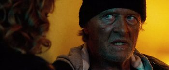 Movie still from “Hobo with a Shotgun” (2011), directed by Jason Eisener – An old man with a beard and a hat on; Close Up shot, Over the shoulder angle