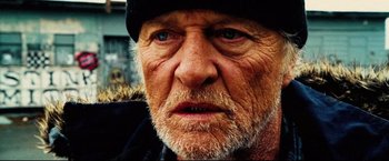 Movie still from “Hobo with a Shotgun” (2011), directed by Jason Eisener – An old man with a beard wearing a black hat; Close Up shot, Low angle