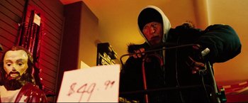 Movie still from “Hobo with a Shotgun” (2011), directed by Jason Eisener – An older man in a hooded jacket holding a cane; Medium shot, Low angle