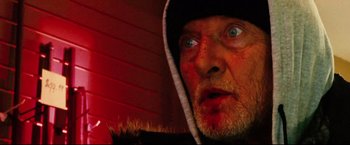 Movie still from “Hobo with a Shotgun” (2011), directed by Jason Eisener – A person wearing a hooded sweatshirt; Extreme Close Up shot, Low angle