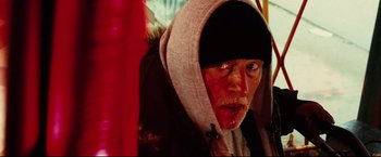 Movie still from “Hobo with a Shotgun” (2011), directed by Jason Eisener – An old man with a beard and a hooded jacket; Close Up shot, Low angle