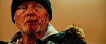 Movie still from “Hobo with a Shotgun” (2011), directed by Jason Eisener – A person with blood on his face; Close Up shot, Low angle
