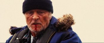 Movie still from “Hobo with a Shotgun” (2011), directed by Jason Eisener – An old man with a beard and a hat on; Close Up shot, Low angle