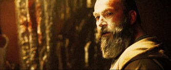 Movie still from “Hobo with a Shotgun” (2011), directed by Jason Eisener – An old man with a long beard looking to his left; Close Up shot, Low angle