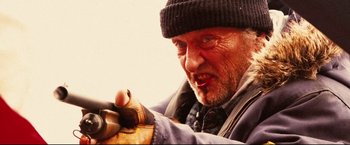 Movie still from “Hobo with a Shotgun” (2011), directed by Jason Eisener – An older man wearing a hat and gloves; Close Up shot, Low angle