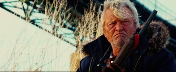 Movie still from “Hobo with a Shotgun” (2011), directed by Jason Eisener – An old man with a white beard is holding a violin; Close Up shot, Low angle