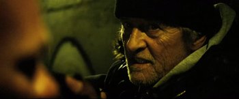 Movie still from “Hobo with a Shotgun” (2011), directed by Jason Eisener – An old man with a beard and a black hat; Close Up shot, Low angle